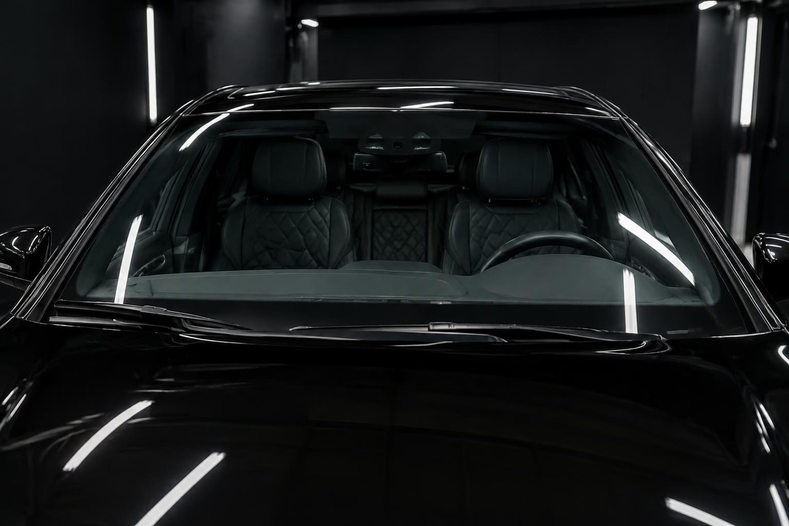 Clear windshield of a black luxury car in a dark garage